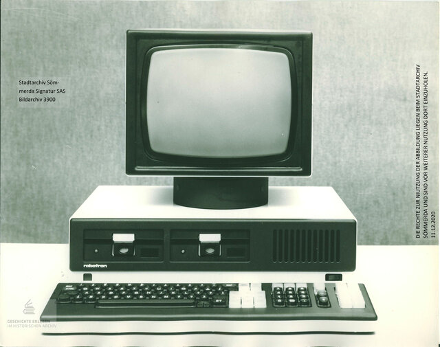 Schwarz-weiß-Fotografie eines DDR-Computers vom Typ Robotron 1715 mit Monitor, zwei Diskettenlaufwerken, Tastatur und Ziffernblock. Die Aufnahme stammt aus dem Bildarchiv des Stadtarchivs Sömmerda (Signatur SAS Bildarchiv 3900).