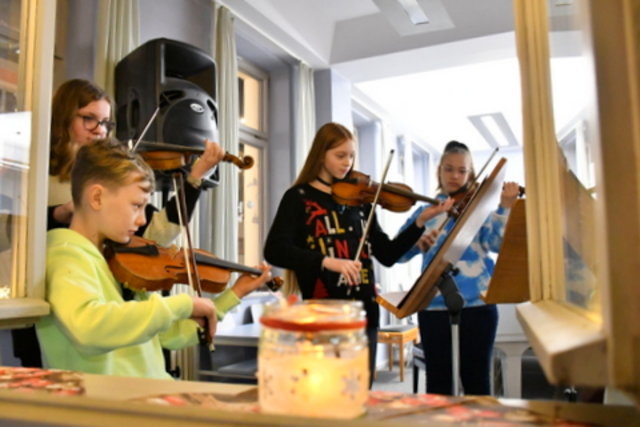 Musikschüler spielen am geöffneten Fenster