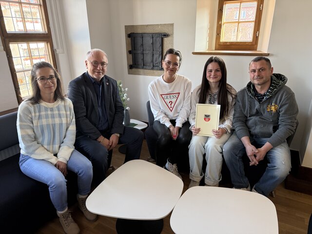 Gruppenfoto im Bürgermeisterzimmer des Rathauses Sömmerda: Bürgermeister, Verwaltungsmitarbeitende, die neue Auszubildende Collien Kühne sowie ihre Eltern sitzen gemeinsam nach der Vertragsunterzeichnung zusammen; die Auszubildende hält ihre Vertragsunterlagen in den Händen.
