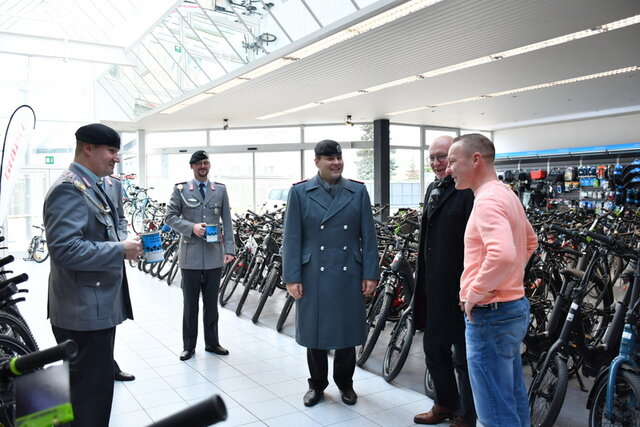 Foto von einer Sammelaktion in den vergangenen Jahren. Foto: Archiv In einem Fahrradgeschäft stehen im Mittelgang zwischen zwei langen Reihen aufgestellter Fahrräder fünf Männer. Drei sind von der Patenkompanie und in Unoform gekleidet. Zwei von ihnen halten je eine Spendenbüchse in einer Hand. Der Bürgermeister spricht mit dem Geschäftsinhaber, die anderen drei Männer hören den beiden zu.