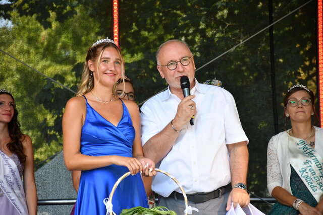 Waidprinzessin Celina I. im königsblauen Kleid mit Krone auf der Bühne des Bauernmarkts 2024 in Sömmerda, neben ihr Bürgermeister Ralf Hauboldt mit Mikrofon in der Hand; im Hintergrund weitere Hoheiten.