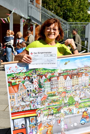 Ina Greyer mit Spendenscheck und Erzählbild