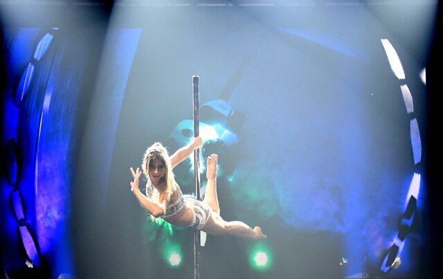 Artistin während einer Pole-Dance-Showeinlage auf der Bühne beim Sportlerball, im Hintergrund farbige Lichtprojektionen.