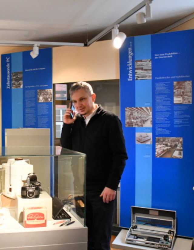 Dr. Dörfler mit Smartphone an einer der Ausstellungsvitrinen im Museum Sömmerda