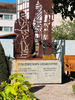 Neues Dreyse-Denkmal im Rosengarten Bronzefarbene Skulptur auf steinernen Sockel zeigt Nicolas von Dreyse im Rosengarten
