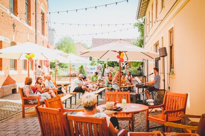 Menschen sitzen im Historischen Rosengarten am Dreyse-Haus und verfolgen eine musikalische Darbietung im Freien.