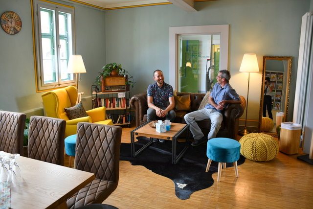 Stefan Schmidt und Bastian Wulf sitzen auf dem neuen Sofa im Lesecafé.