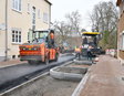 Die Asphaltschicht wird mit einer großen Walze festgewalzt.