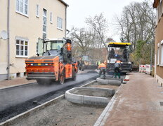 Die Asphaltschicht wird mit einer großen Walze festgewalzt.