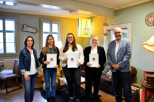 Personalleiterin Sabine Felske steht mit den zukünftigen Auszubildenden und Bürgermeister Ralf Hauboldt im Lesecafe der Stadt- und Kreisbibliothek mit den Veträgen in der Hand