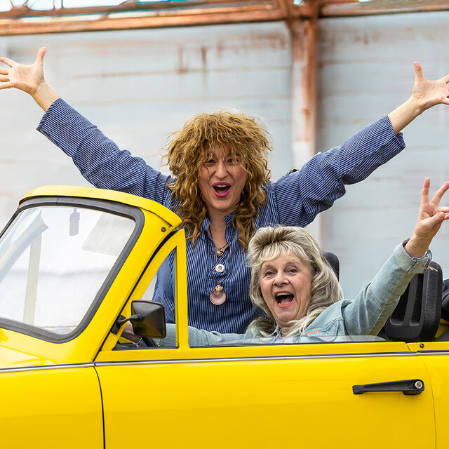 Bild zeigt 2 Frauen, die ein einem gelben Trabbi-Caprio sitzen
