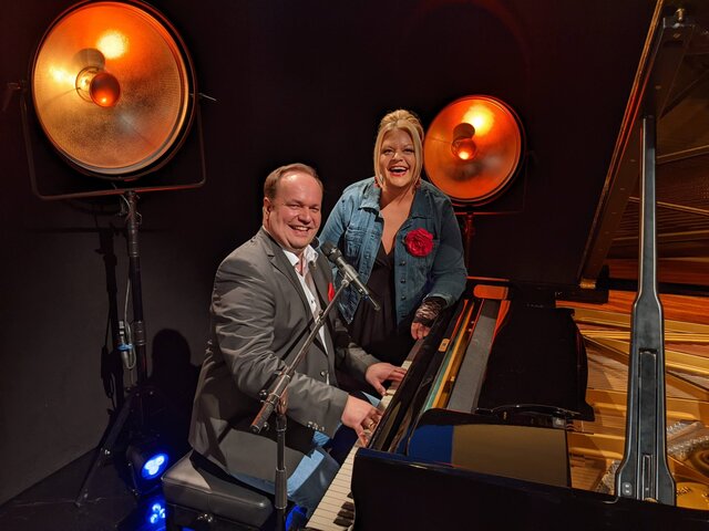 Tine Wittler und Arndt Baeck am Klavier lachen in die Kamera.