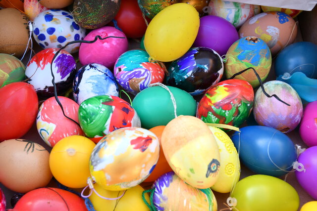 Farbenfrohe bemalte Ostereier Bunte, handbemalte Ostereier liegen nebeneinander in einem Eierkarton. Die Eier sind mit verschiedenen Farben und Mustern verziert, darunter Punkte, Streifen und Blumenmotive. Einige Eier haben Fäden zum Aufhängen. Das Sonnenlicht fällt von der Seite auf die Eier und hebt die leuchtenden Farben hervor.