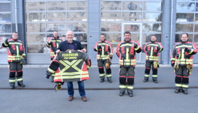 Feuerwehrleute stehen in neuer Einsatzkleidung vor der Feuerwache