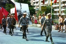 Historische Aufnahme eines Festumzugs in Sömmerda mit Teilnehmern in Kostümen und roten Fahnen auf einer Straße vor Zuschauern.