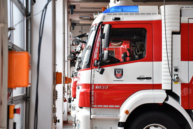 Mehrere rote Feuerwehrfahrzeuge der Freiwilligen Feuerwehr Sömmerda stehen einsatzbereit in der Fahrzeughalle der Feuerwache. Die Seitenansicht zeigt die Beschriftung „Feuerwache 1“ sowie Details wie Außenspiegel, Blaulicht und Technikanschlüsse.