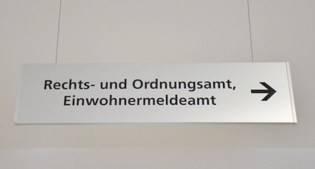 Ein Schild hängt von der Decke im Eingangsbereich des Verwaltungsgebäudes Poststraße. Das Schild weist die Richtung zum Rechts- und Ordnungsamt sowie Einwohnermeldeamt.