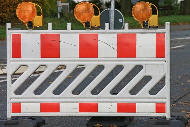 gesperrte Straße mit weiß roter Warnbarcke und orangen Warnlichtern