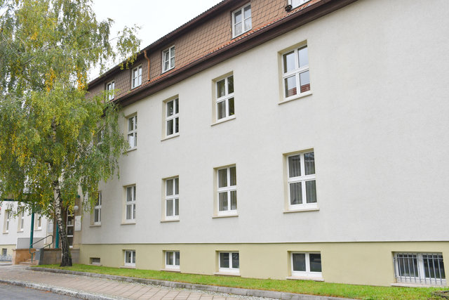 Ein Haus mit mehreren Etagen und einem Baum am Eingangsbereich. In dem Haus in der Poststraße 1 ist die Straßenverkehrsbehörde zu finden.