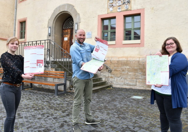 Mitarbeiterinnen der Tourist-Information und der Abteilungsleiter Kultur mit dem Stadtplan vor dem Rathaus