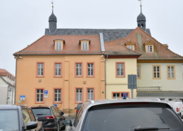 Blick über parkende Autos auf die Rathaus-Rückseite