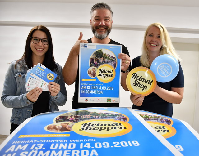 Lisa Rötting, Thomas Hollenbach und Mandy Stegmann zeigen Werbematerial für die Aktion Heimat shoppen. 