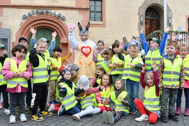 Osterparty auf dem Obermarkt Kinder mit Warnwesten und der Osterhase stehen gemeinsam vor dem Rathaus in Sömmerda und winken in die Kamera.