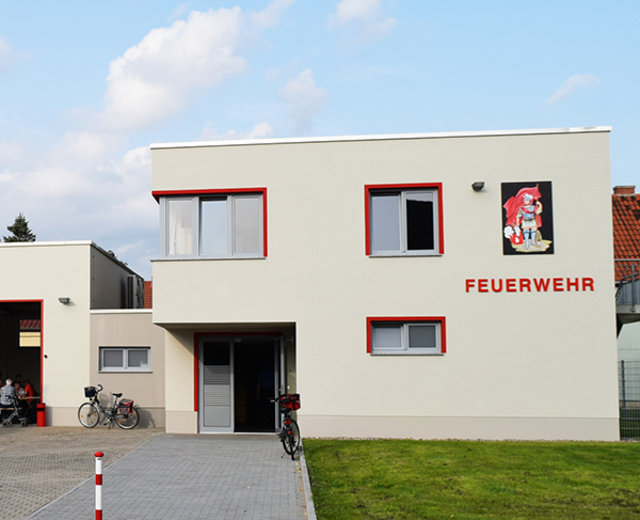 Ein flaches, zweistöckiges Gebäude, an dessen Fassade Feuerwehr steht.