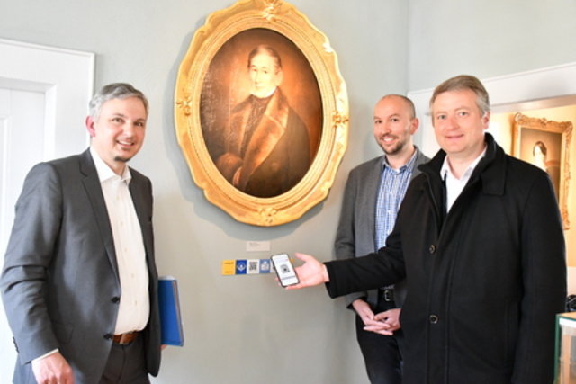 Dr. Hans-Diether Dörfler, Stefan Schmidt und der 1. Beigeordnete Christian Karl mit Smartphone an einer Audioguide-Station im Museum.