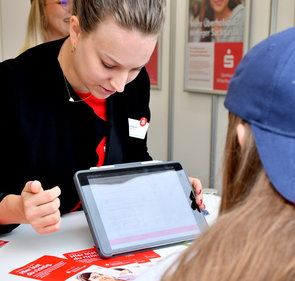 Eine Mitarbeiterin der Sparkasse beim Gespräch mit einer Schülerin