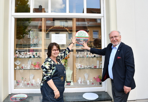 Katrin Ewald und Bürgermeister mit Aufklaber vor der Goldschmiede Lompe