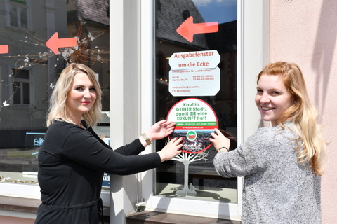 Lena Kob und Nora Probst mit Aufkleber vor der Tourist-Information