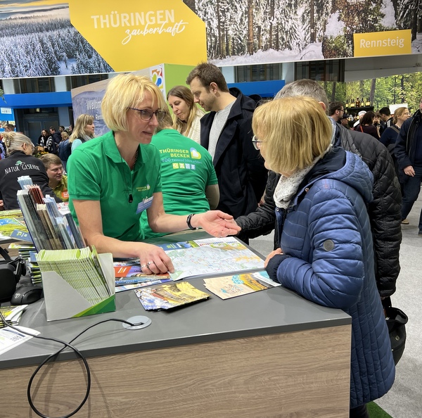 Eine Vertreterin des Tourismusverbandes spricht am Stand mit Besuchern.