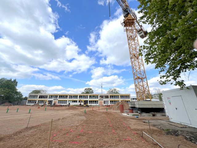 Der Baugrund für den Neubau ist eingeebnet. Recht steht der hohe Kran. Im Hinter steht das zweistöckige alte Kita-Gebäude, das im zweiten Bauabschnitt abgerissen wird.