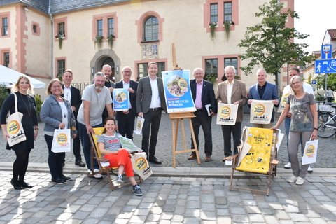 Beteiligte des Heimat shoppens mit Plakaten, Beuteln und Aufklebern vor dem Rathaus