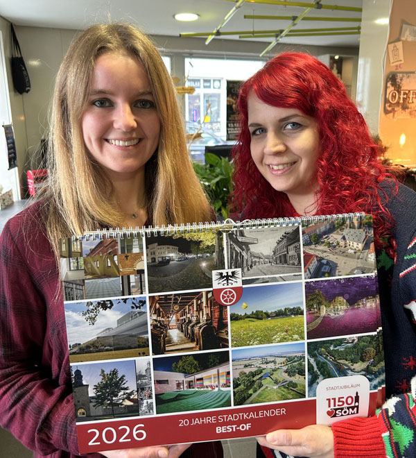 Die zwei Mitarbeiterinnen der Tourist-Information Sömmerda präsentieren das Titelblatt des Sömmerda-Kalender 2026. Auf dem Titelblatt sind alle 12 Kalenderblätter des komenden Jahres zu sehen.