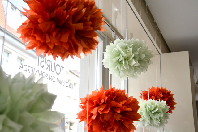 Ein Schaufenster, in dem rote und weiße große, künstliche Blumenblüten hängen.