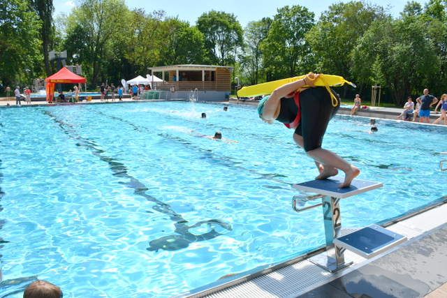 Eine Rettungsschwimmerin steht auf dem Startblock des Schwimmerbeckens im Stadtbad und ist zum Startsprung bereit.