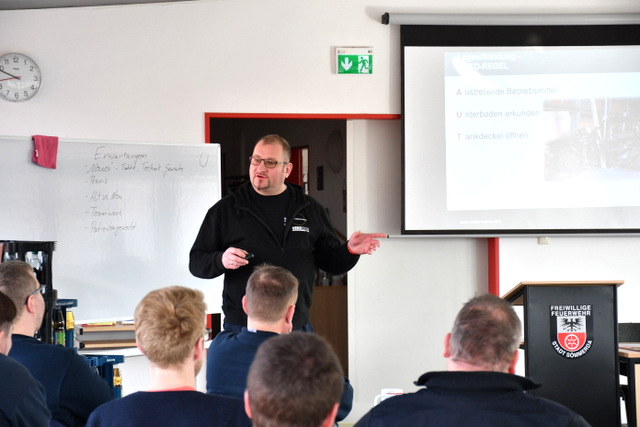 Ein Mitarbeiter der Ausbildungsfirma steht im Schulungsraum vor Mitgliedern der Feuerwehr und erklärt, auf was bei der Rettung von Personen aus einem verunfallten Pkw zu achten ist.