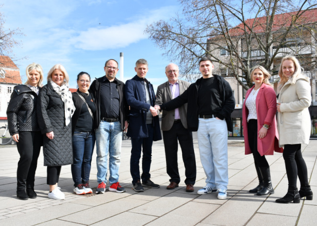 Frauen und Männer stehen in einer Reihe. Bürgermeister und zwei Vertreter der Interessengemeinschaft Kneipenmeile geben sich die Hand als Zeichen für die Annahme der Wette.