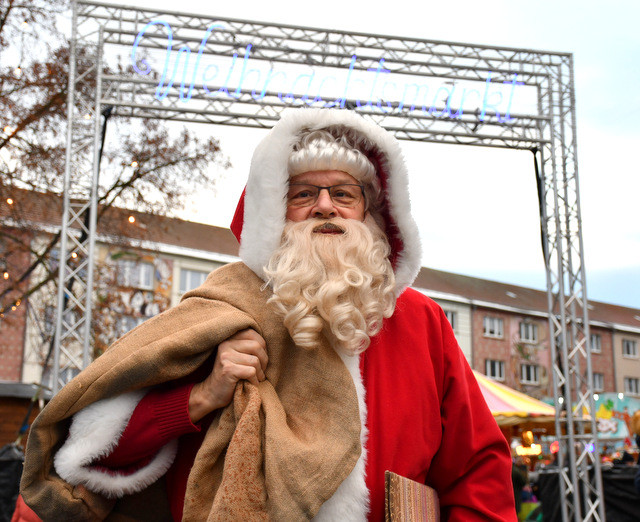 Mann als Weihnachtsmann verkleidet. Im Hintergrund sind die Stände auf dem Obermarkt zu sehen